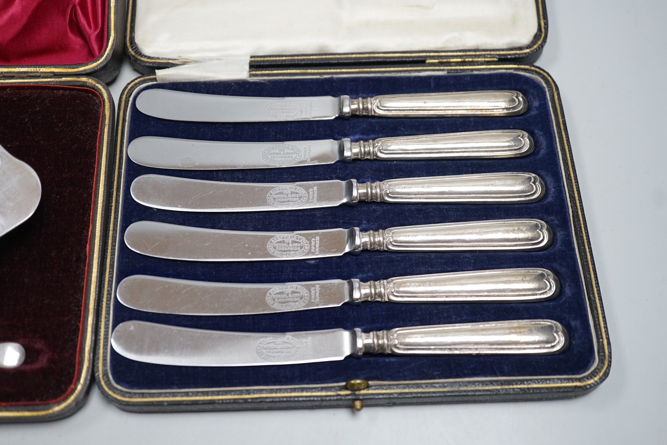 A set of six tea knives, an Edwardian silver butter shell and knife and a set of six silver coffee spoons, all cased.